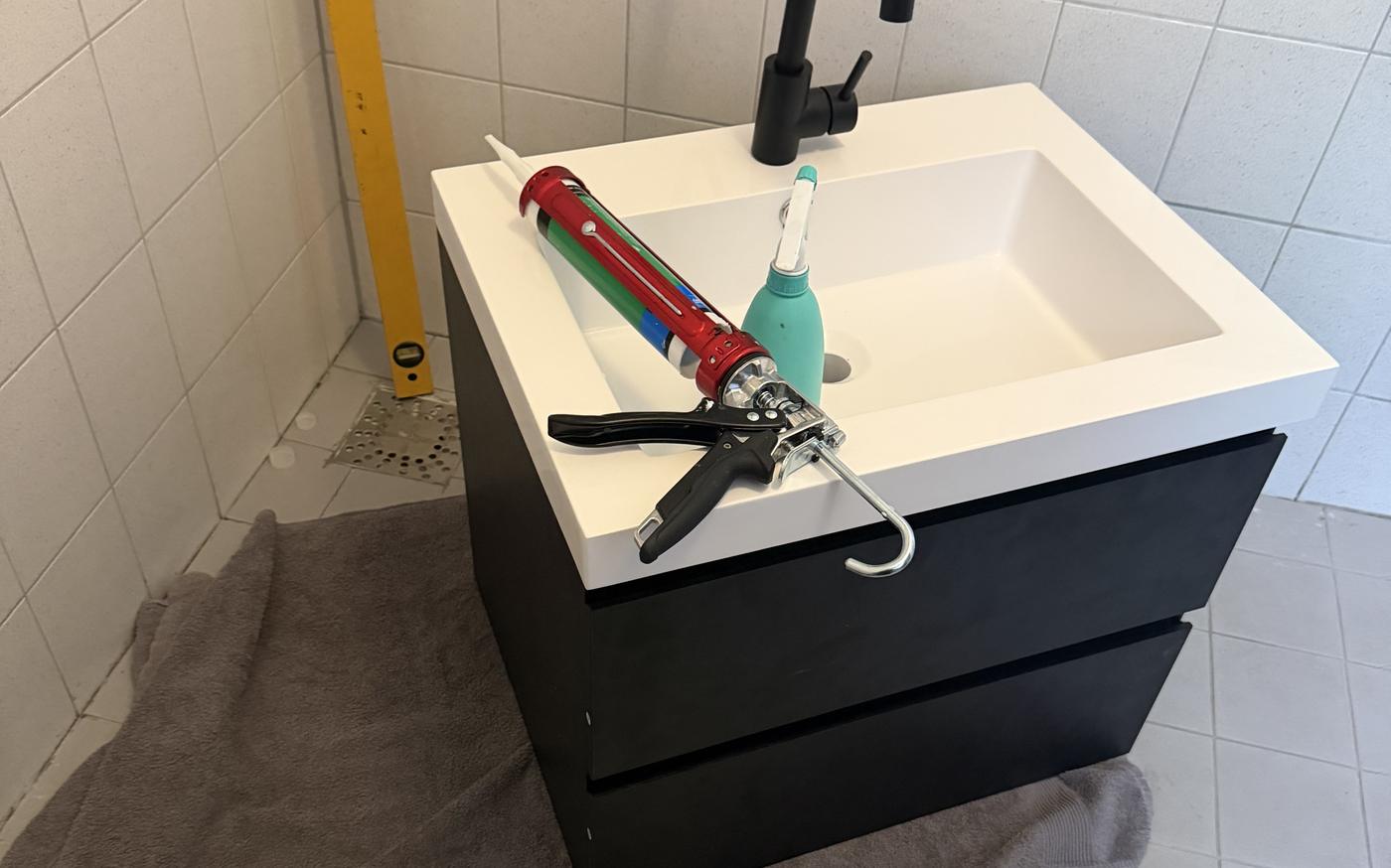 Nieuw badkamermeubel geplaatst, met kitpistool ernaast